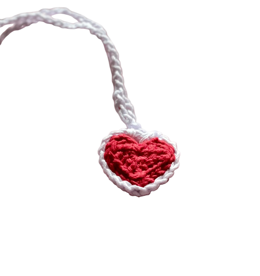 A crocheted red heart with white lace on a white crocheted pendant