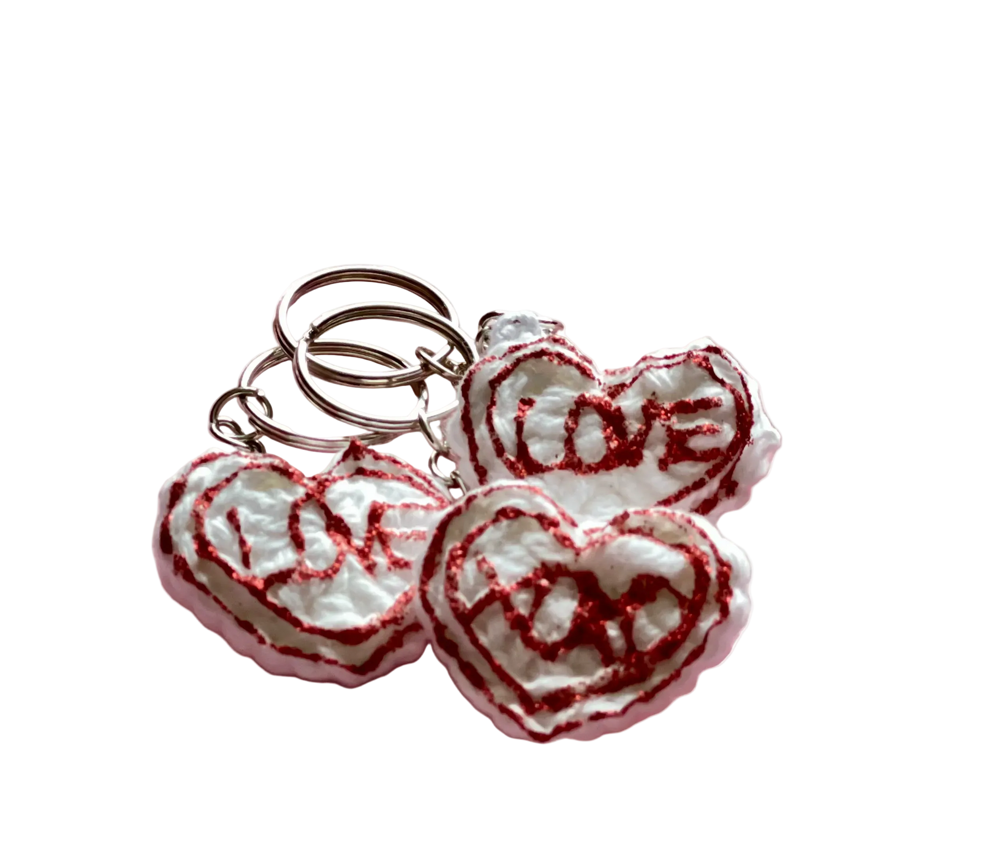 Crocheted white hearts with red lettering reading "love" and "xoxo" attached to keychain rings