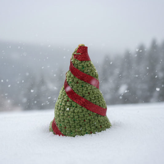 Small crocheted Christmas tree with glittery ornaments and red ribbon