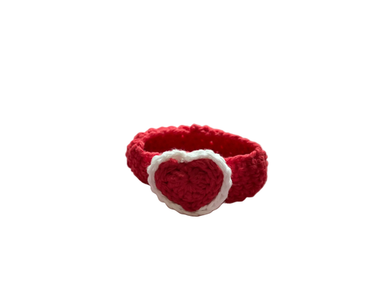 A crocheted red heart with white lace attached to a red crocheted wristband