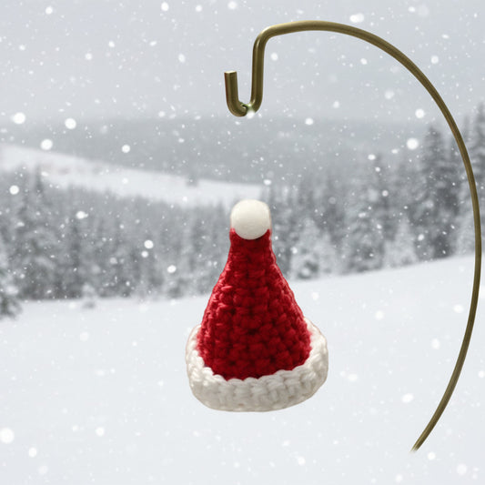 A small red and white crocheted santa hat hanging ornament