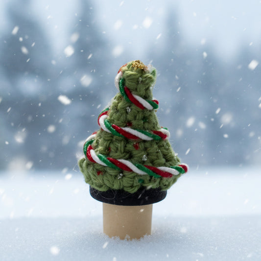 Small crocheted Christmas tree with glittery ornaments and a green, red, and white tricolor ribbon